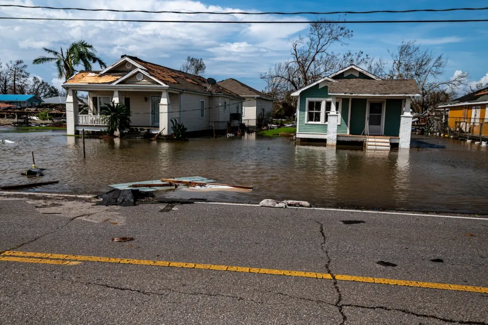 Two small wooden one-story homes in Florida with floodwaters at their doors.